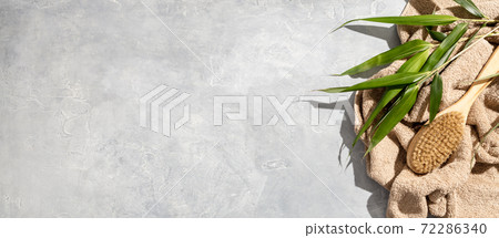 Anticellulite natural brush, towel and bamboo leaves on concrete background Anticellulite natural brush, towel and bamboo leaves on concrete background 72286340