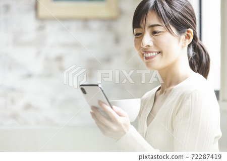 A woman relaxing with a smartphone 72287419