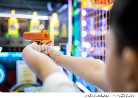 Asian little child playing shooting game for a carnival while visiting in the shopping mall,happy kid boy holding a toy gun in hands,aim and shoot the target,the annual festival at Christmas,New year 72288156