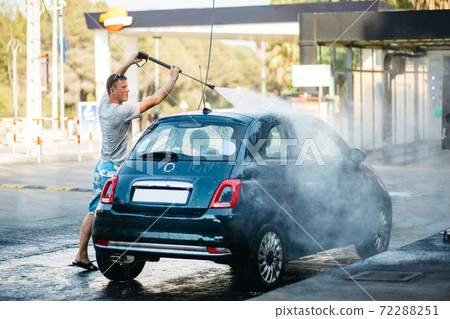 Car wash. The man cleans the car with water under high pressure on a sink. Summer car wash. 72288251