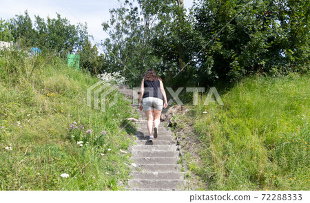Woman climbing old concrete overgrown with grass stairs Woman climbing old concrete overgrown with grass stairs 72288333