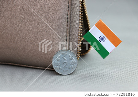 Two Rupee money coin of India and mini Indian flag stick on the leather wallet on grey background. 72291810