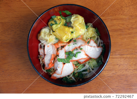 egg noodle and pork wonton with red roasted pork in the Japanese bowl on the wooden table. egg noodle and pork wonton with red roasted pork in the Japanese bowl on the wooden table. 72292467