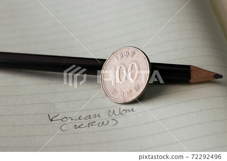 One hundred Korean won coin on reverse, (KRW) with black pencil on the book. One hundred Korean won coin on reverse, (KRW) with black pencil on the book. 72292496
