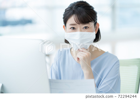 Woman wearing a mask in the office Woman wearing a mask in the office 72294244