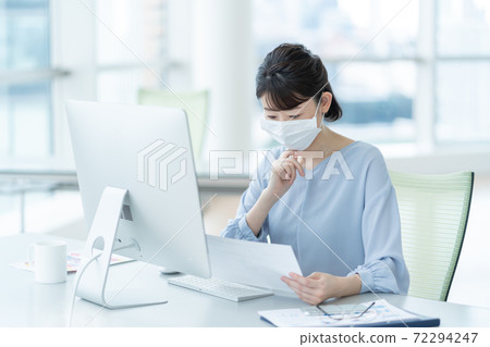A woman working with a mask in the office A woman working with a mask in the office 72294247