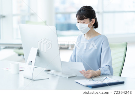 A woman working with a mask in the office 72294248