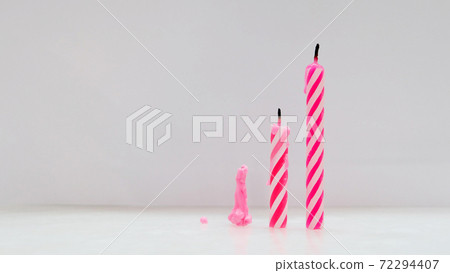 Three extinguished pink birthday candles in different heights, placed on top of a surface side by side from short to tall. Three extinguished pink birthday candles in different heights, placed on top of a surface side by side from short to tall. 72294407