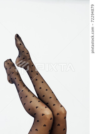 beautiful slender women's legs in black tights on a white background beautiful slender women's legs in black tights on a white background 72294879