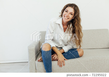 Beautiful woman sits on a gray office sofa in a white house room Beautiful woman sits on a gray office sofa in a white house room 72295022