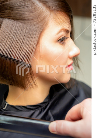 Hairdresser straightening short brown hair 72295135