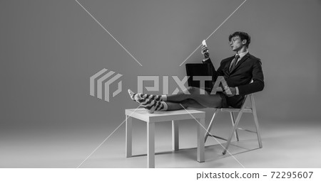 Young fashionable, stylish man wearing jacket and socks working from home. Fashion during insulation 'cause of coronavirus pandemic Young fashionable, stylish man wearing jacket and socks working from home. Fashion during insulation 'cause of coronavirus pandemic 72295607