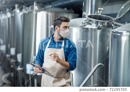 Factory employee works with equipment for industrial beer production 72295705