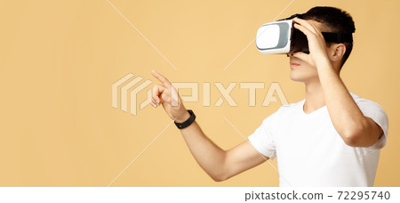 Serious young guy student in white t-shirt and virtual reality glasses touches to free space 72295740