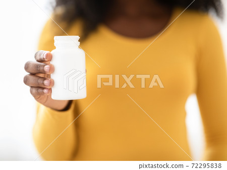 Closeup of black pregnant woman holding white jar with medication 72295838