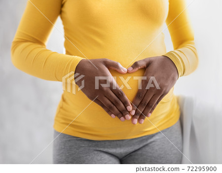 Pregnant woman holding palms in heart shape on her tummy 72295900