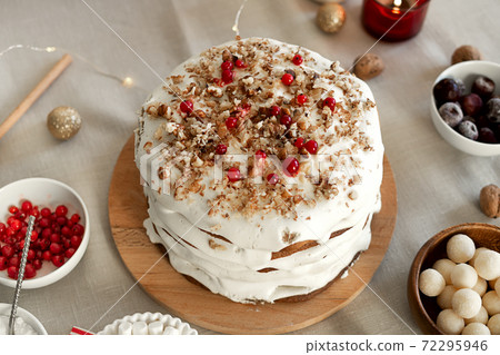 Preparing food for Christmas dinner. Homemade Christmas cake with white icing sugar, nuts and red cranberries 72295946
