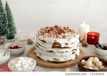 Preparing food for Christmas dinner. Homemade Christmas cake with white icing sugar, nuts and red cranberries Preparing food for Christmas dinner. Homemade Christmas cake with white icing sugar, nuts and red cranberries 72295956