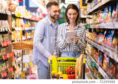 Young couple with shopping list in supermarket Young couple with shopping list in supermarket 72295988