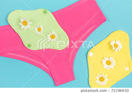 Eco reusable menstrual pads and underpants with chamomiles on blue background. Health care and zero-waste, no plastic concept. Top view Flat lay Close-up 72296630