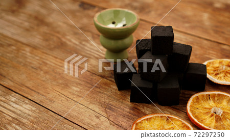 Coals for hookah on wooden background with dry oranges Coals for hookah on wooden background with dry oranges 72297250