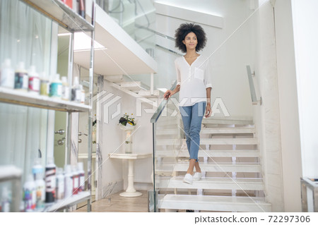Joyful young woman on steps in beauty center Joyful young woman on steps in beauty center 72297306
