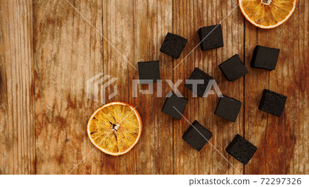 Coals for hookah on wooden background with dry oranges Coals for hookah on wooden background with dry oranges 72297326