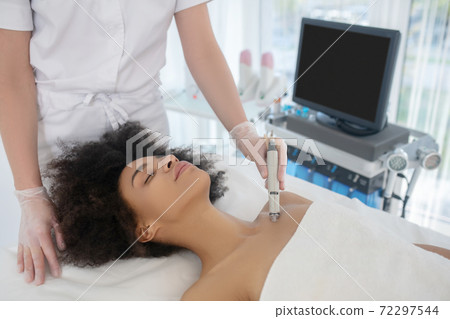 Young woman reclining during procedure in cosmetic center 72297544