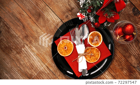 Christmas dinner decoration with dried oranges and a red napkin on a black plate 72297547