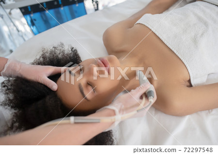 Woman receiving modern cosmetic procedure and doctor hands 72297548