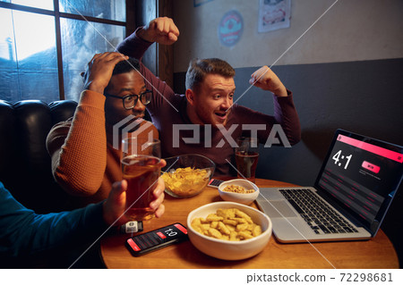 Excited fans with mobile app for betting and score on their devices. Gambling, emotions Excited fans with mobile app for betting and score on their devices. Gambling, emotions 72298681