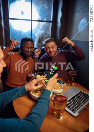 Excited fans with mobile app for betting and score on their devices. Gambling, emotions Excited fans with mobile app for betting and score on their devices. Gambling, emotions 72298703