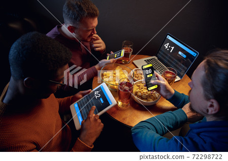 Excited fans with mobile app for betting and score on their devices. Gambling, emotions 72298722