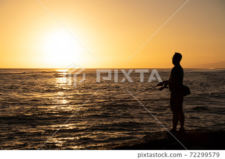 Silhouette of a person fishing against the backdrop of the Hawaiian sunset Silhouette of a person fishing against the backdrop of the Hawaiian sunset 72299579