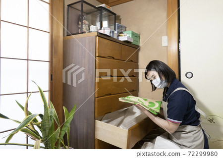 A female worker assessing a kimono in a chest of drawers A female worker assessing a kimono in a chest of drawers 72299980
