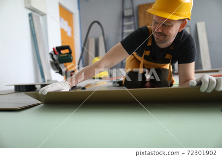 Man hold laminate panel and lay on floor on soft pad in room. 72301902