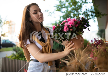 cute young woman holding her favorite flowers in a street garden shop cute young woman holding her favorite flowers in a street garden shop 72302704