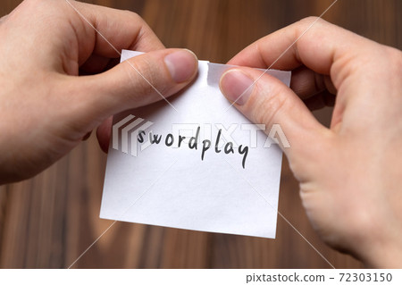 Hands tearing off paper with inscription swordplay 72303150