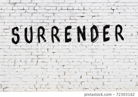 Word surrender painted on white brick wall 72303182