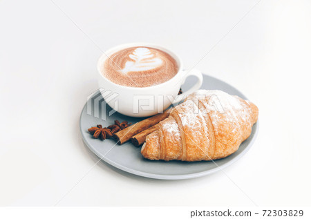 Fresh baked croissant with coffee cup and latte art, cinnamon 72303829