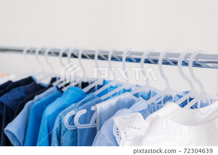 Fast fashion, Sustainable fashion, minimalist wardrobe. Variety of female blue clothing on hanging on white background with copy space. Fashion minimal style banner Fast fashion, Sustainable fashion, minimalist wardrobe. Variety of female blue clothing on hanging on white background with copy space. Fashion minimal style banner 72304639
