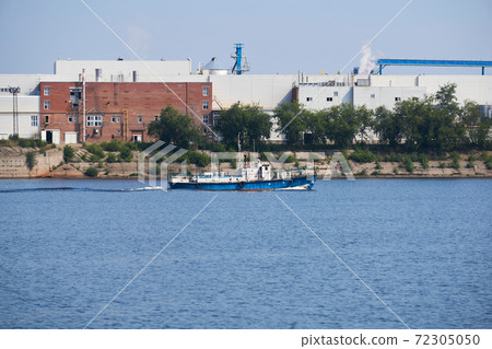 industrial landscape with a factory on the banks of the river, along which a motorship floats 72305050