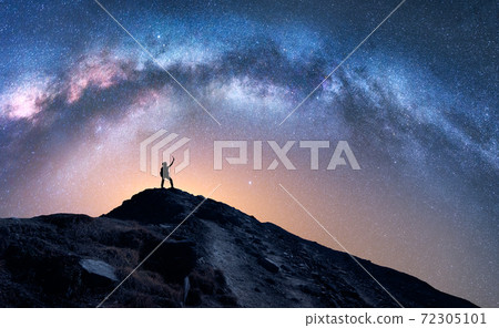 Arched Milky Way and happy man on the mountain at night 72305101