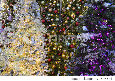 tall artificial spruces. the trees are decorated with beautiful, shiny, colorful balls. toys for decorating Christmas trees. colorful garlands on the fir trees, bright illumination 72305381