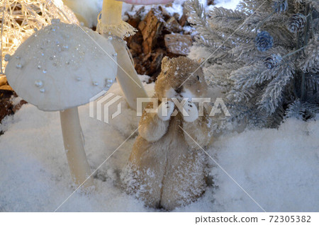 shop window decoration, shopping center decor. artificial white spruce with garlands. next to them, a cute white animal is standing on two legs. furry ferret enjoys winter 72305382