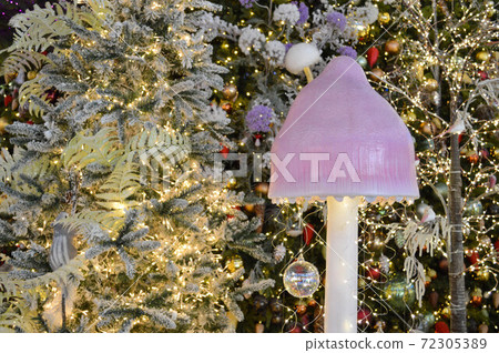 shop window decoration, shopping center decor. artificial white spruce with garlands. beneath them is a mushroom with a large pink cap. cute christmas forest for shop window decor shop window decoration, shopping center decor. artificial white spruce with garlands. beneath them is a mushroom with a large pink cap. cute christmas forest for shop window decor 72305389