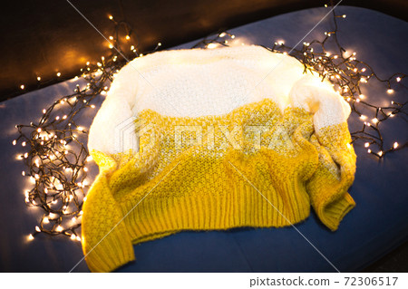 Knitted sweater placed on light garland. Trendy colors of the year Knitted sweater placed on light garland. Trendy colors of the year 72306517