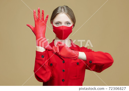 young girl puts on red gloves and a face mask. Concept for preventing coronavirus covid 19. young girl puts on red gloves and a face mask. Concept for preventing coronavirus covid 19. 72306827