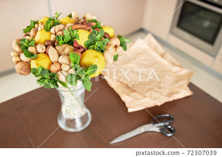 Beautiful fruit bouquet and cutted wrapping paper for packing lie on the table Beautiful fruit bouquet and cutted wrapping paper for packing lie on the table 72307039