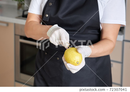 A woman forces on a lemon on a stick making a blank for her fruit bouquet, close-up A woman forces on a lemon on a stick making a blank for her fruit bouquet, close-up 72307041